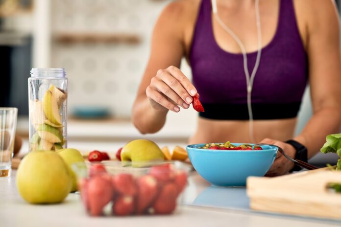 Close-up of female athlete making fruit salad in the kitchen.